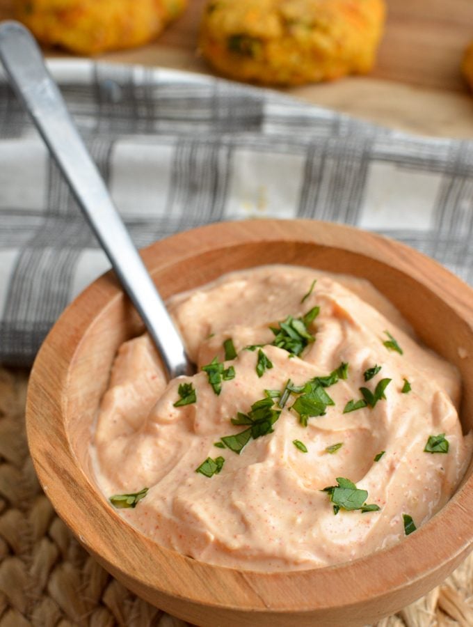 Louisiana remoulade dip in wooden bowl with patties in background with spoon