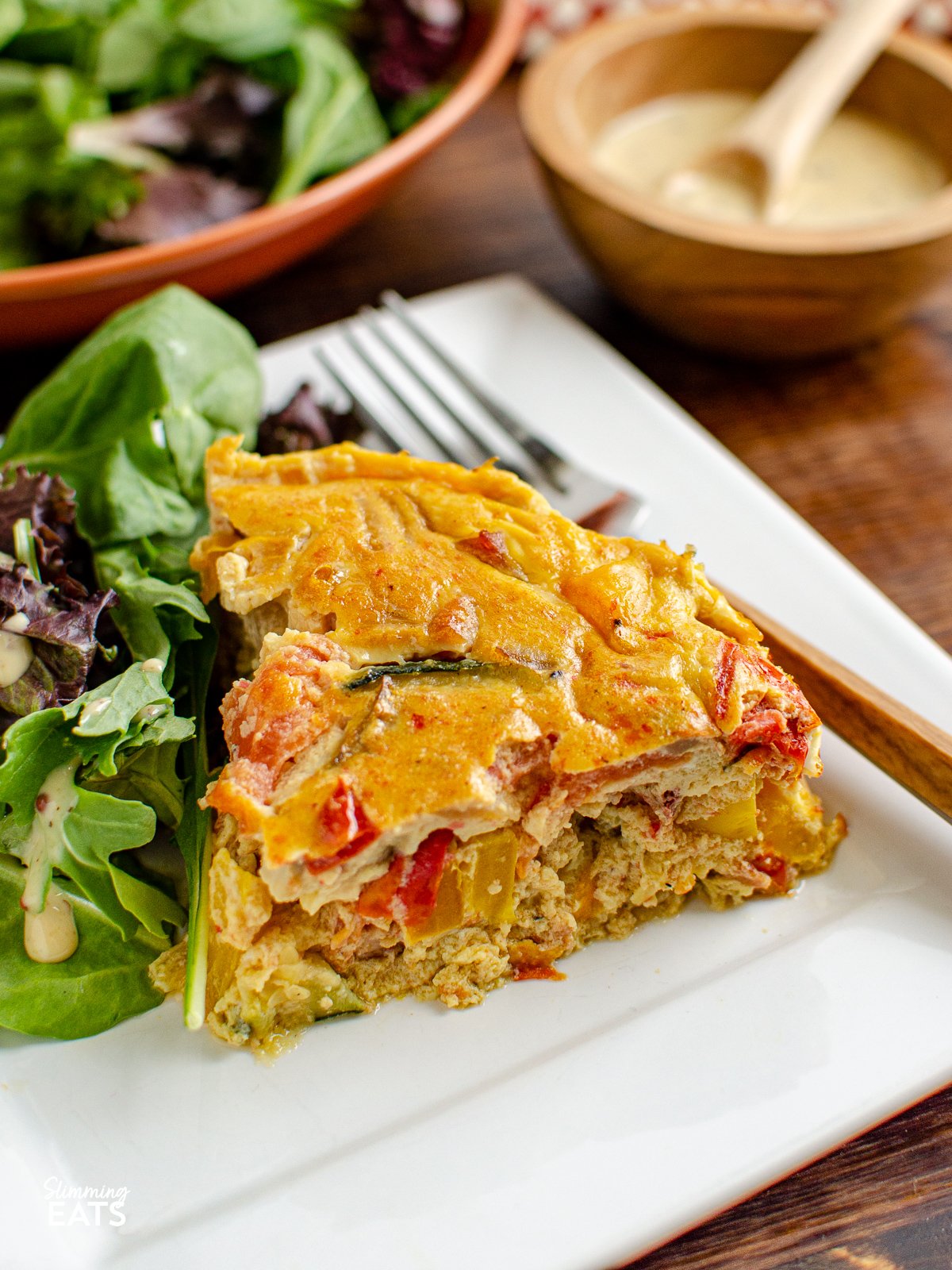 slice of Dairy Free Crustless Bacon and Vegetable Quiche  on white plate with salad