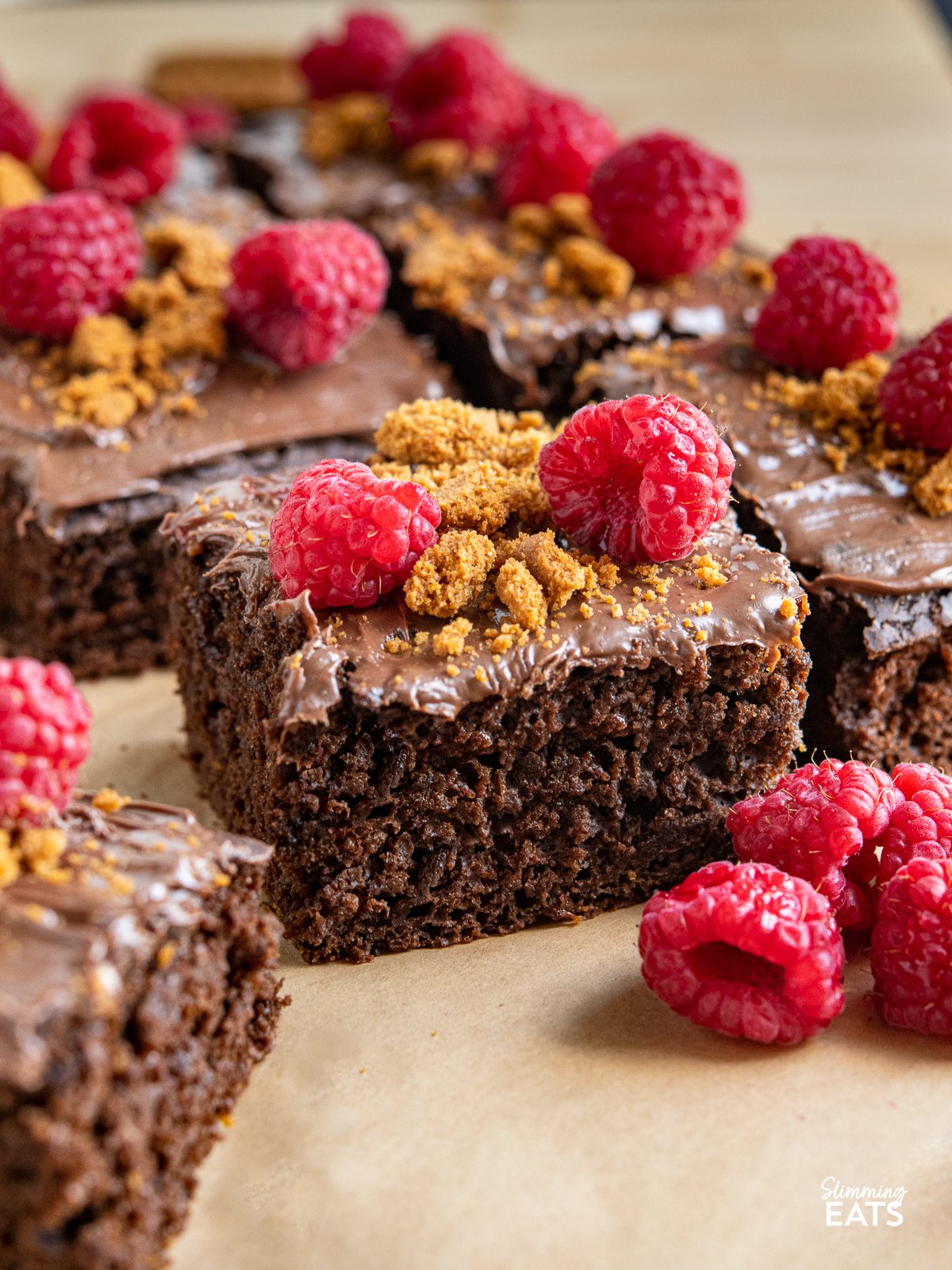 close up of slice of Raspberry Nutella Chocolate Cake with raspberries in front and other slices behind