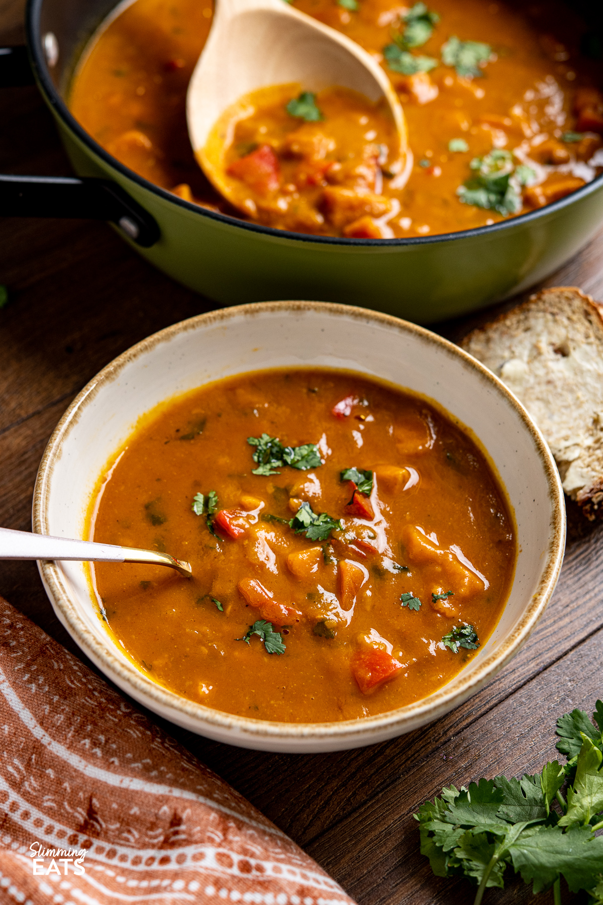 Sweet Potato, Red Pepper and Carrot Soup in a white bowl with spoon