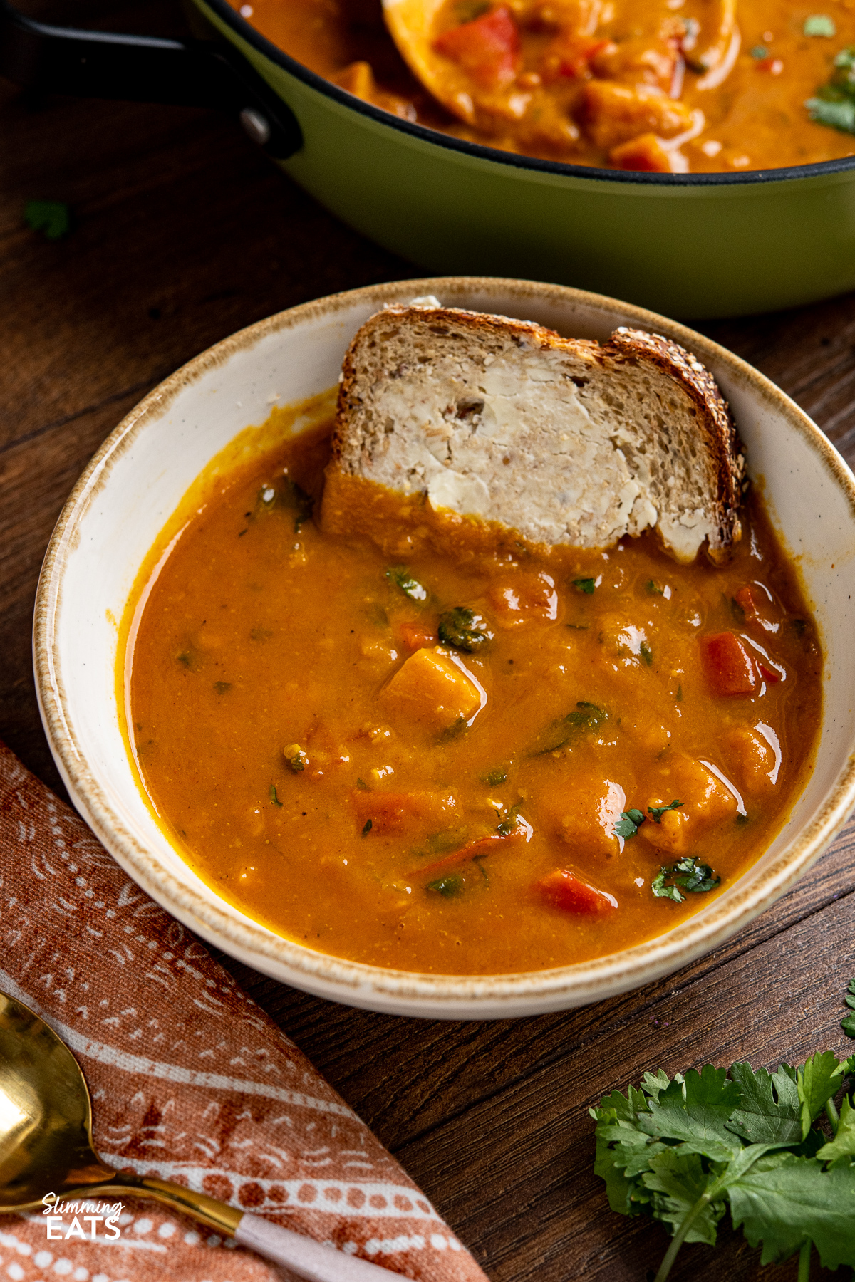 close up of Sweet Potato, Red Pepper and Carrot Soup with small slice of buttered bread