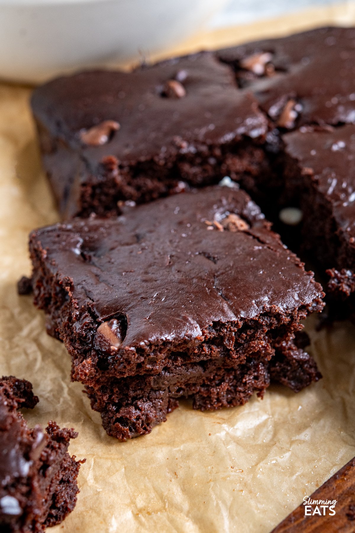 Close-up of a slice of squidgy chocolate cake on parchment paper, highlighting its moist texture.