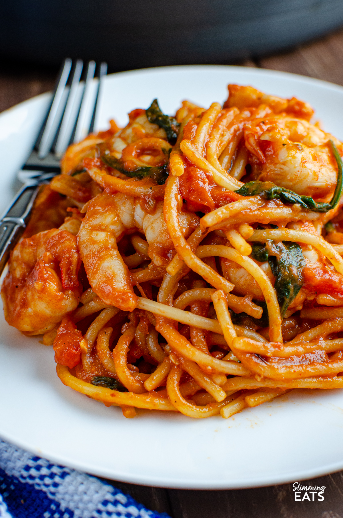 Shrimp and Spinach Tomato Pasta served on a pristine white plate, with a fork poised on the side.