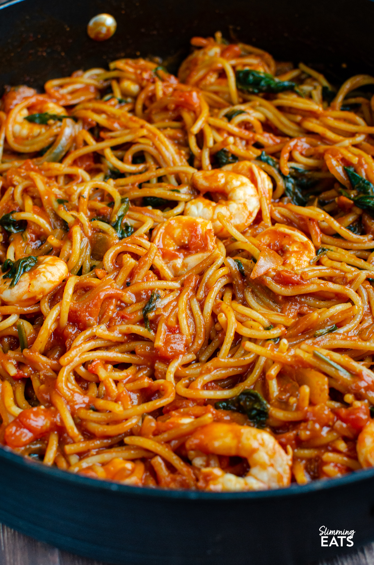 
Shrimp and spinach tomato pasta simmering in a non-stick deep frying pan, ready to be served up fresh and flavorful.