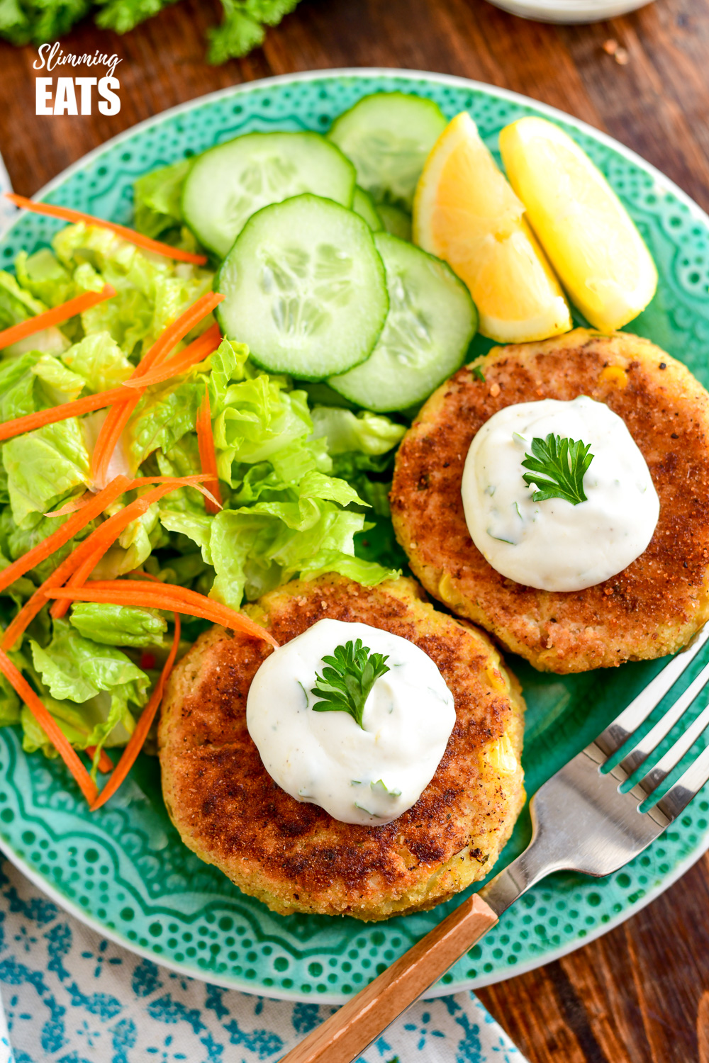 over the top view of crab cakes on a green plate with side salad