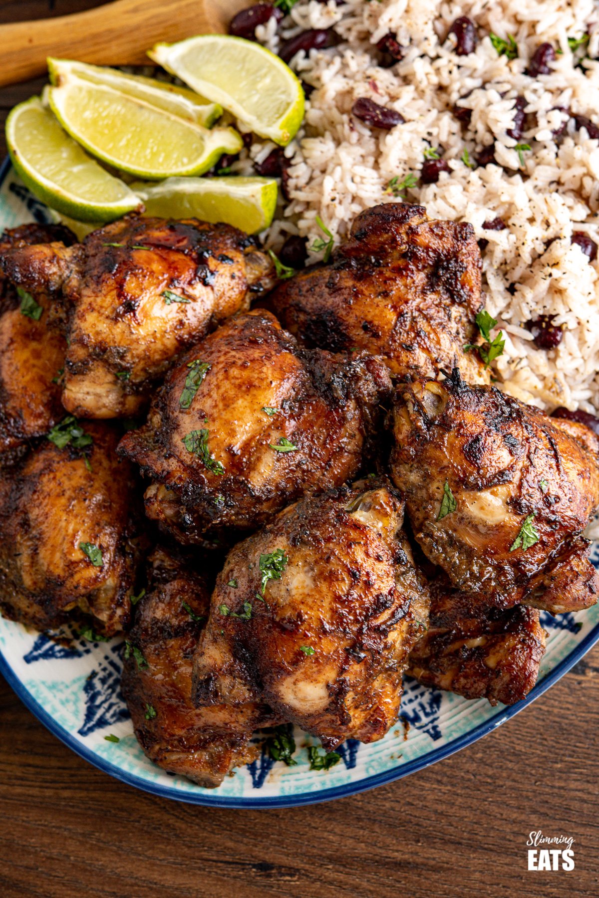 close up close up of large patterned oval plate with Jamaican Jerk Chicken with Rice and Peas and lime wedges