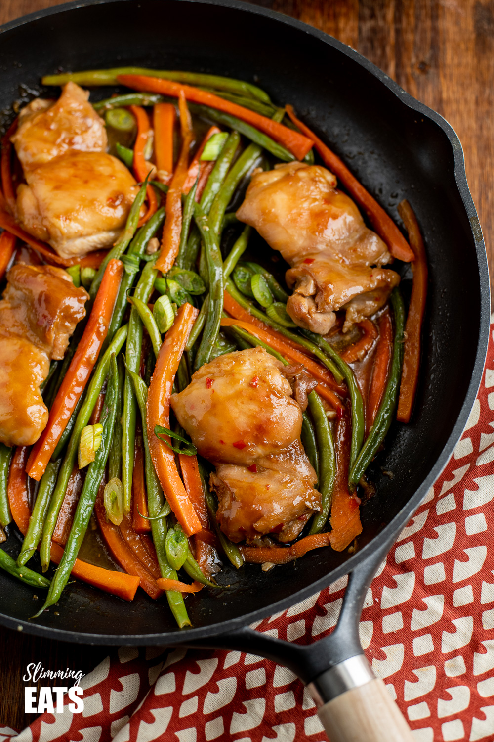 thai spiced chicken in black frying pan with wooden handle