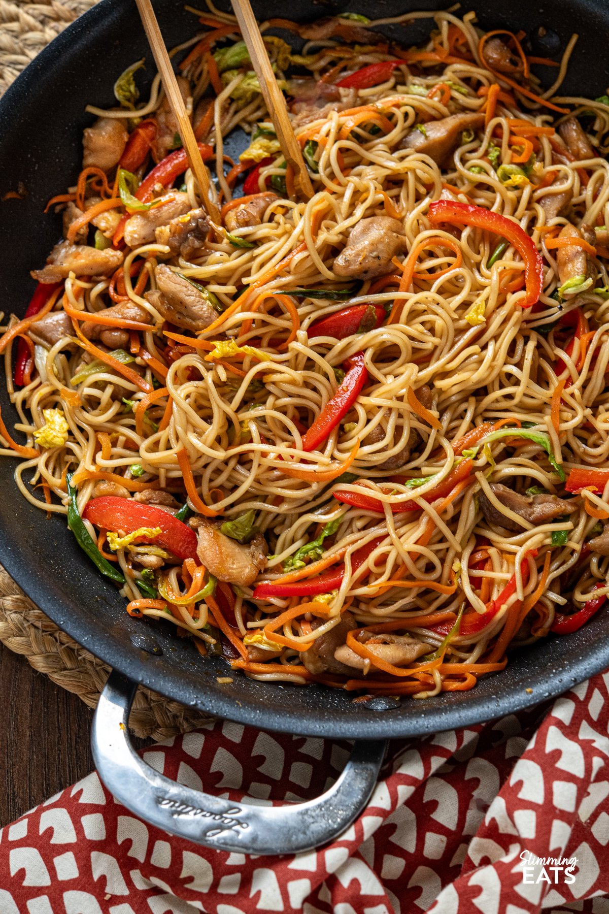 close up of Yakitori Chicken Noodles with Colorful Veggies in a Pan with  Wooden Tongs placed in the noodles