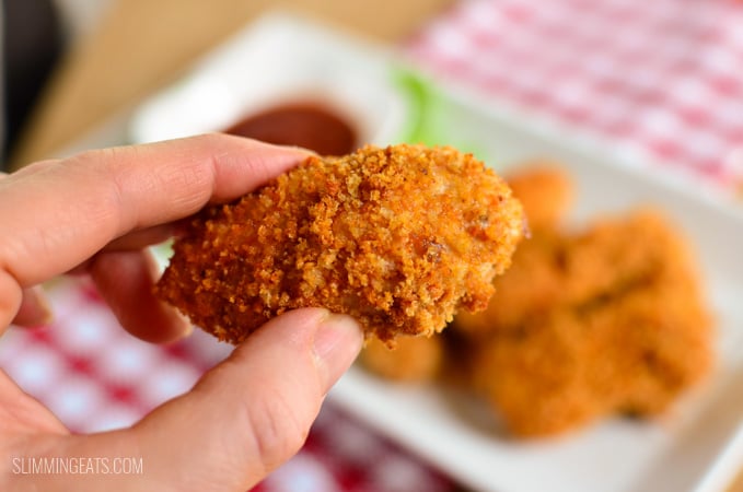 chicken finger in hand ready to dip in ketchup