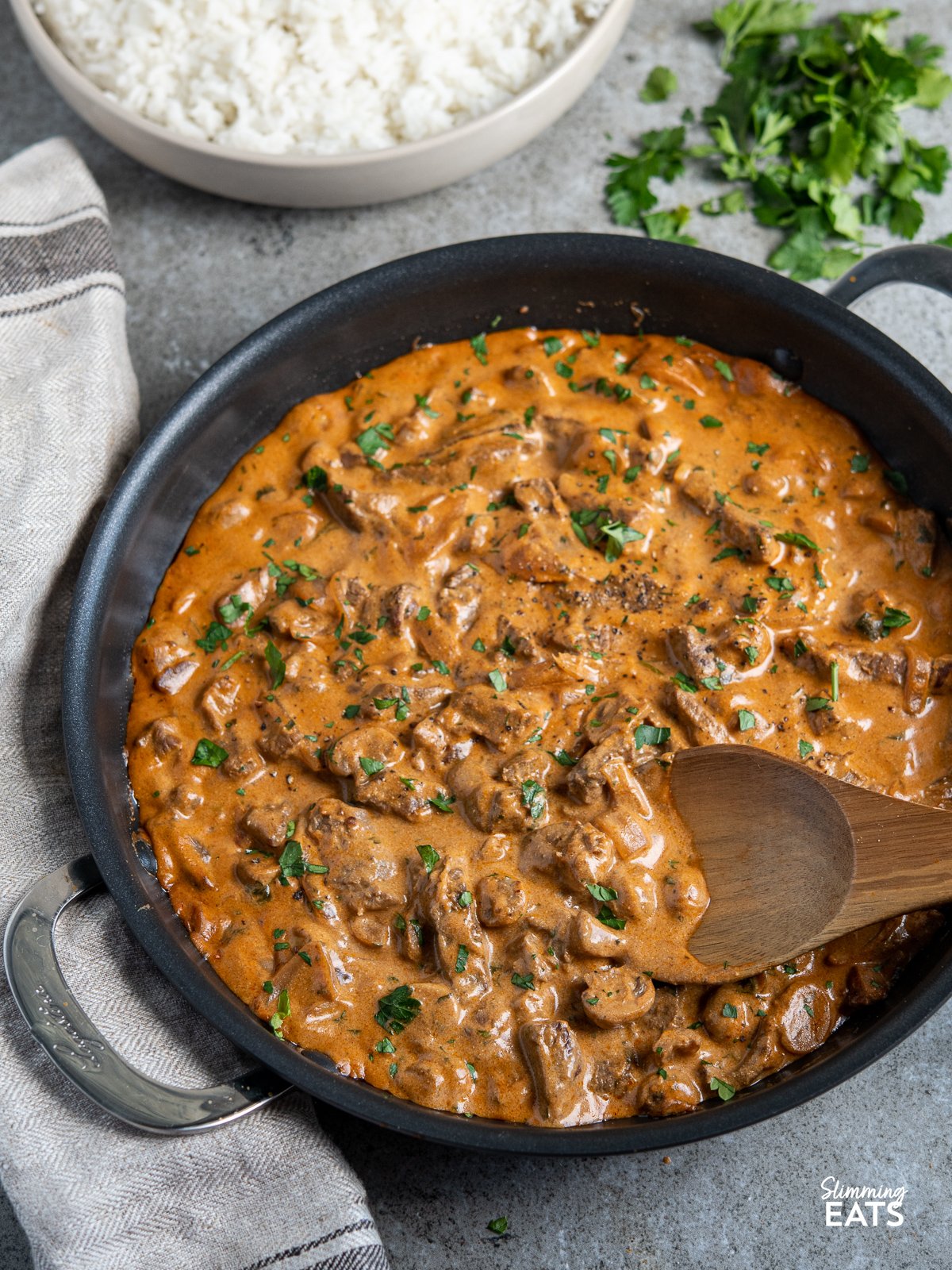 Beef Stroganoff in black frying pan with wooden spoon