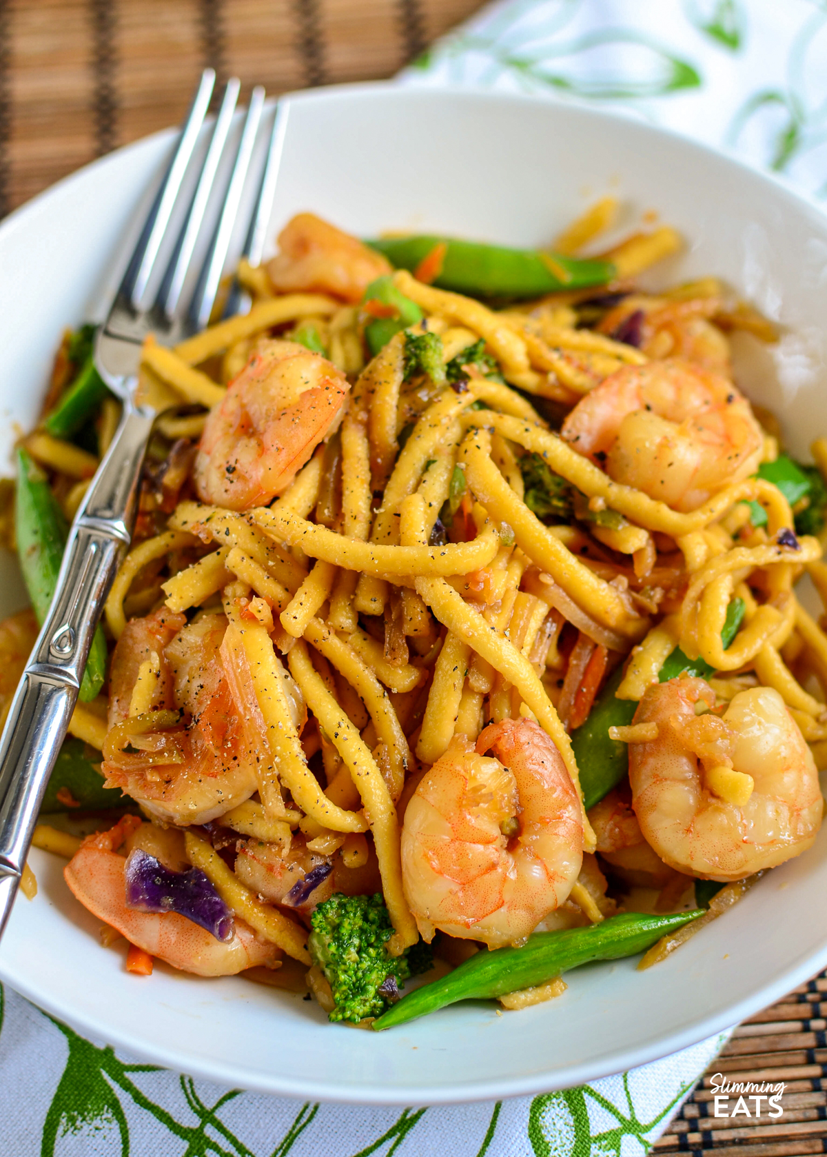 Garlic Ginger Shrimp Noodles - a quick and easy noodle dish packed with juicy shrimp, garlic, fresh ginger and a delicious savoury sauce, all ready in under 20 minutes. It is the perfect busy weeknight dinner. Ginger Garlic Shrimp Noodles in a white bowl with fork