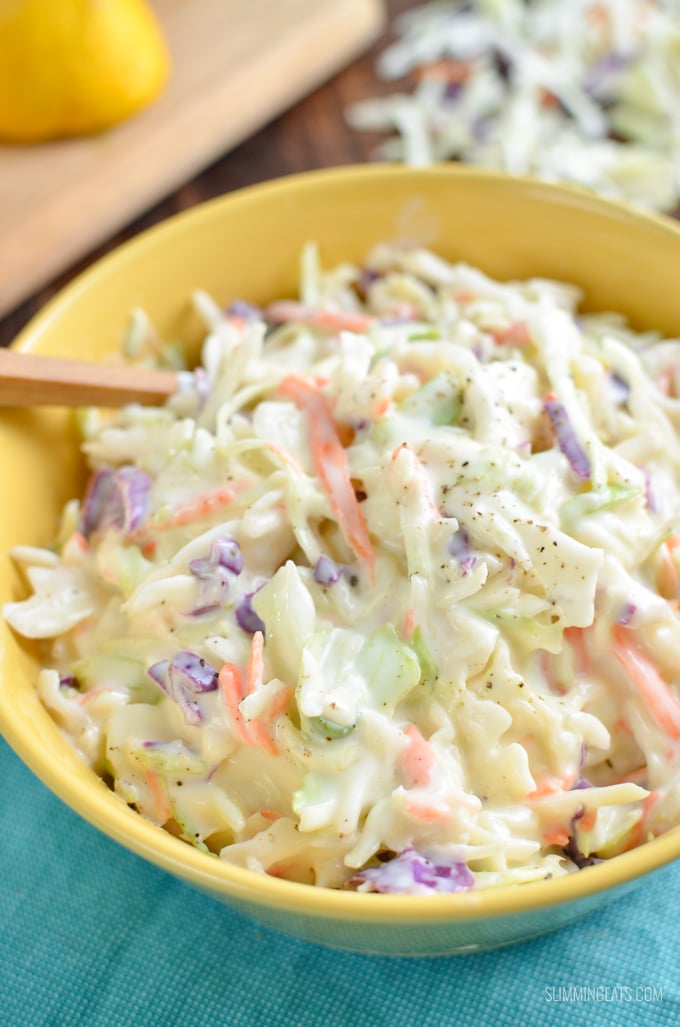 homemade coleslaw in yellow bowl sprinkled with a pinch of black pepper