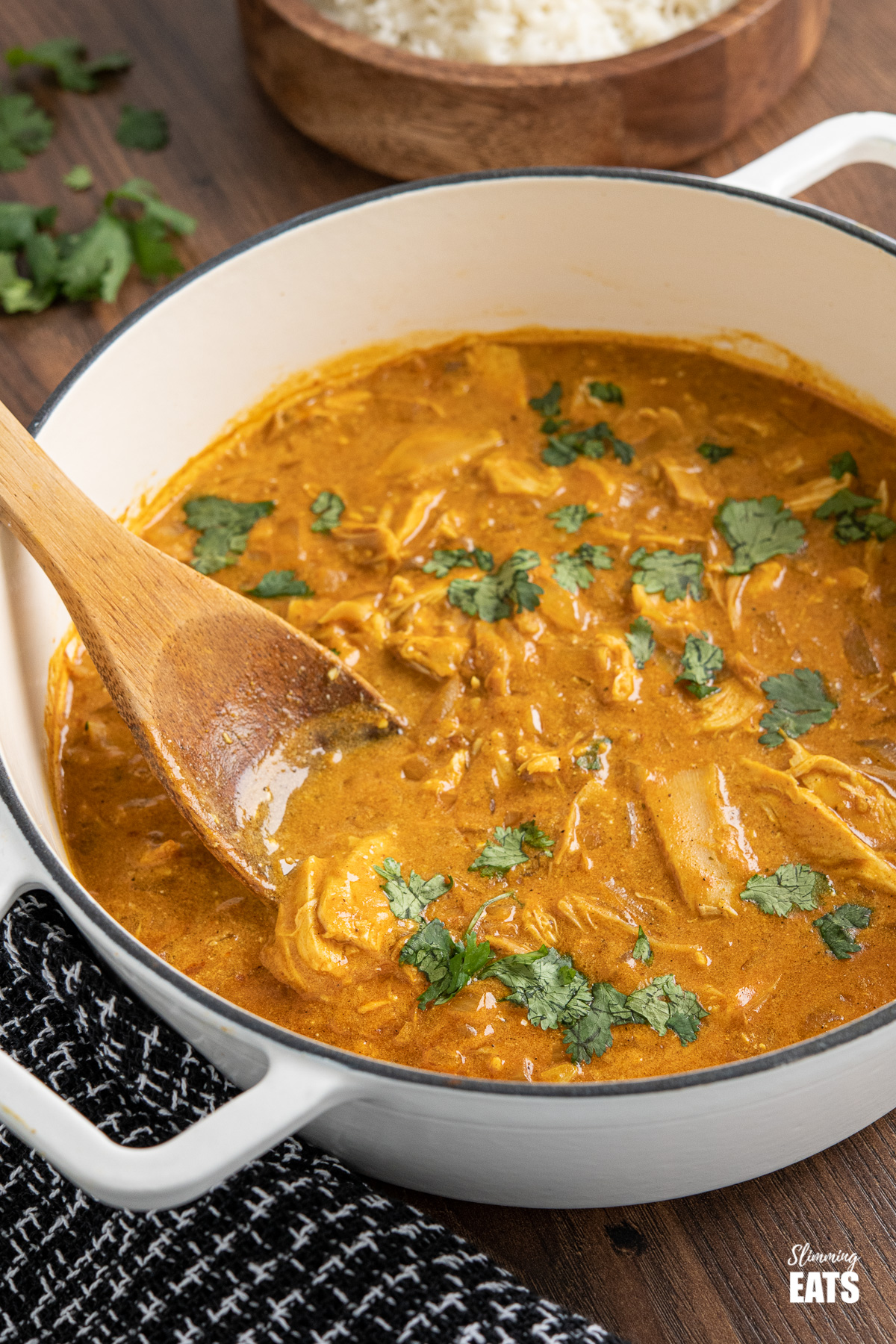 mild chicken curry in white cast iron skillet with wooden spoon