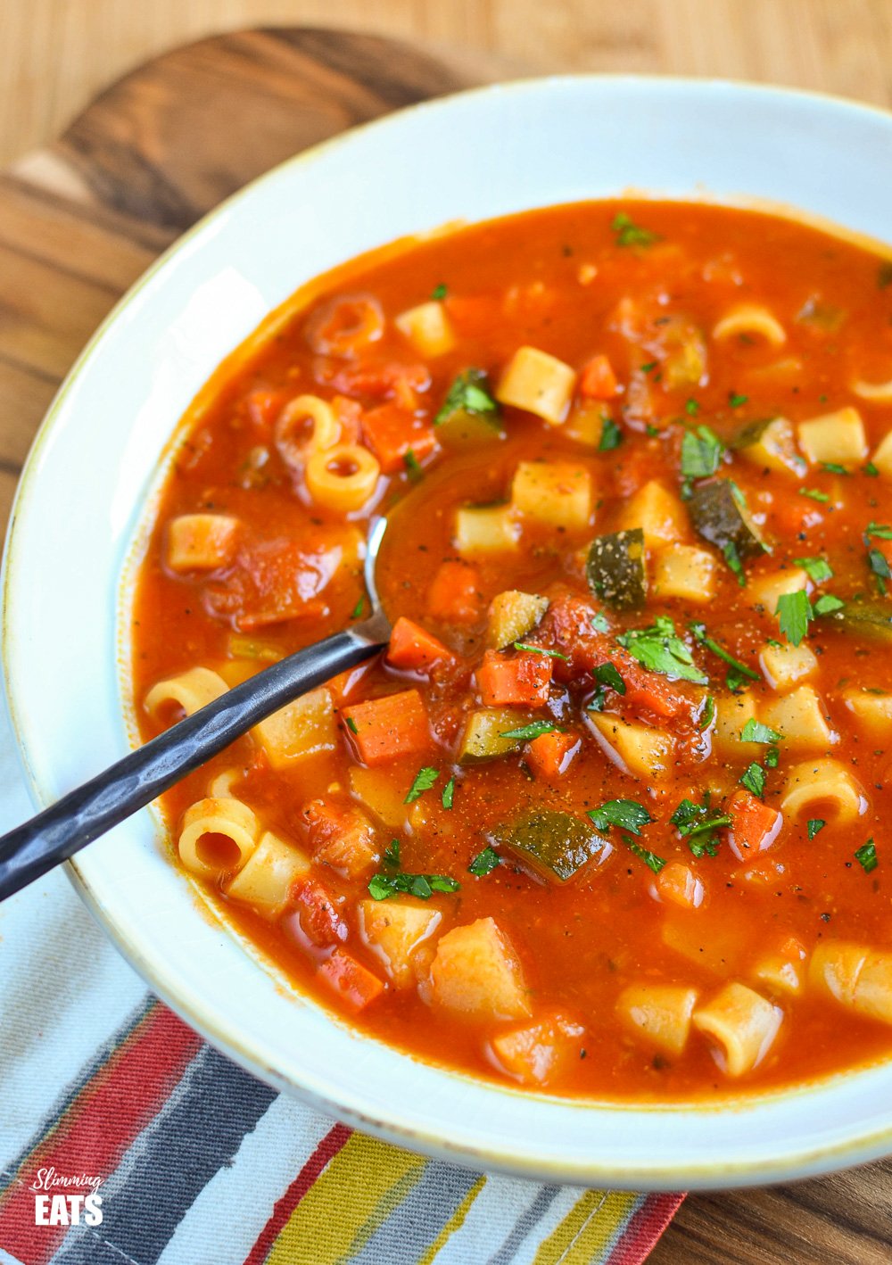 Syn Free Minestrone Soup - hearty soup packed with healthy vegetables, potato and pasta. Dairy free, vegetarian, Slimming World and Weight Watchers friendly white bowl of minestrone soup with black handled spoon