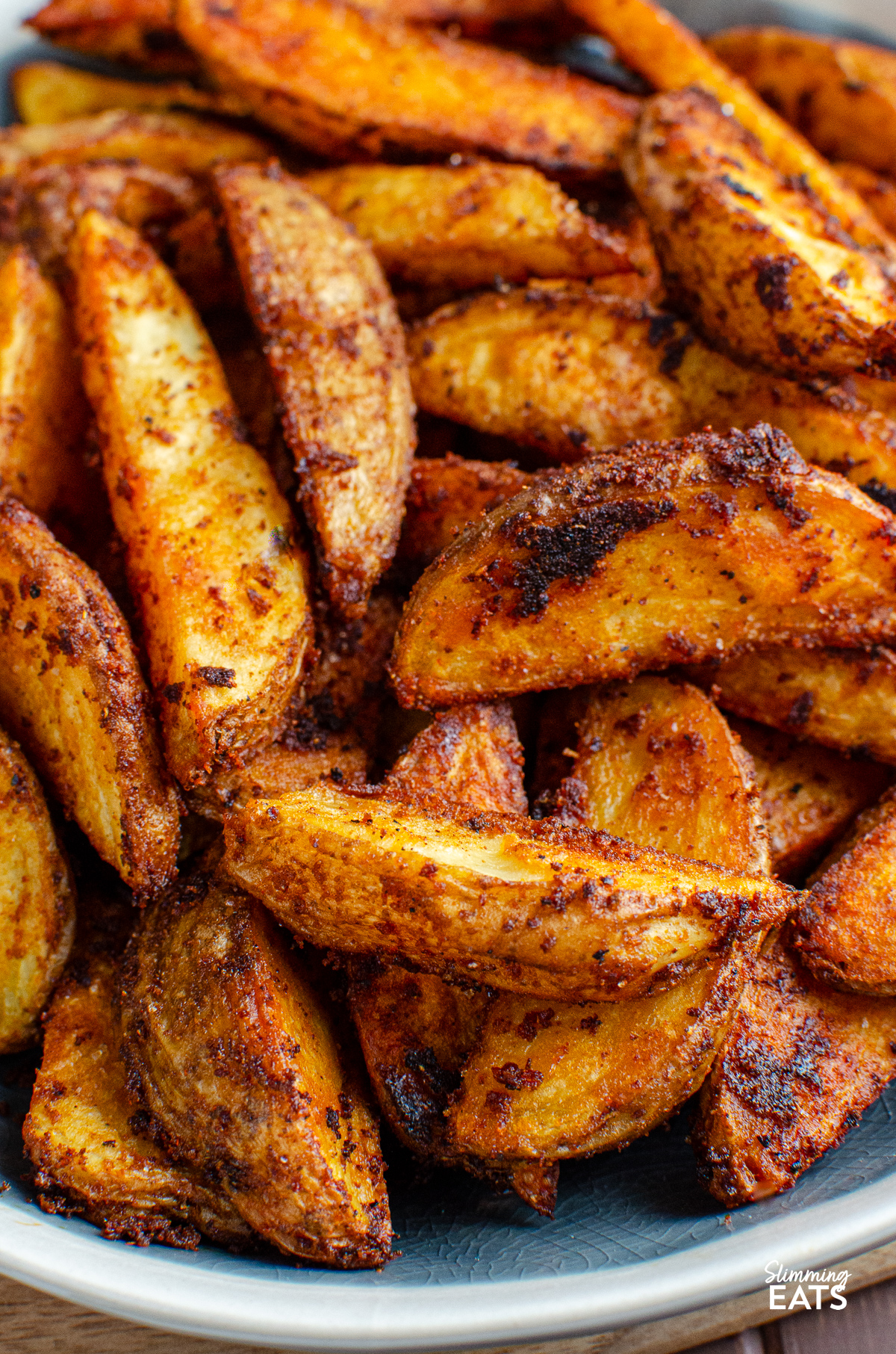 close up of Spicy potato wedges in a blue-gray bowl with white rim