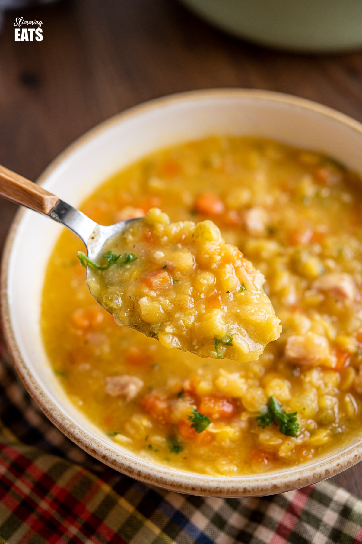 spoon scooping split pea and bacon soup from cream coloured bowl