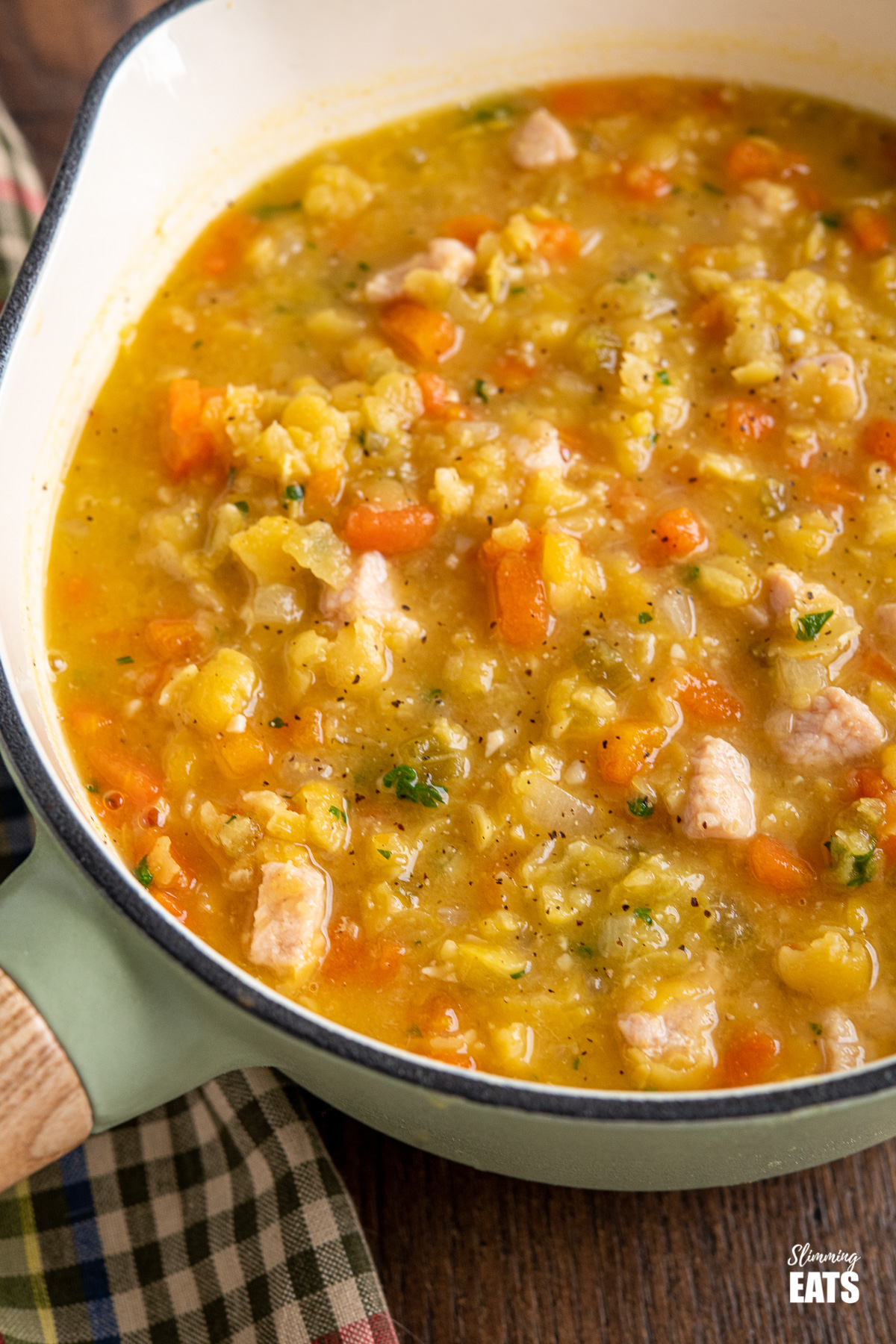close up of split pea and bacon soup in wooden handles cast iron saucepan