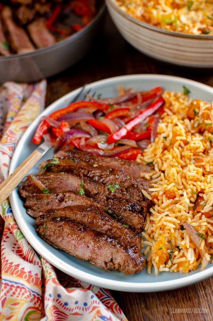 marinated mouth-watering steak on grey blue plate with peppers, onion and roasted butternut squash rice