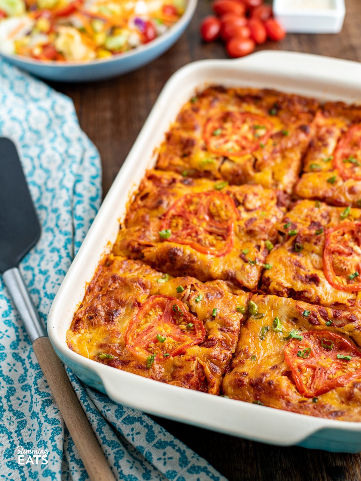 Spicy Mexican Chicken Lasagne, portion up in oven baking dish with wooden spatula to left
