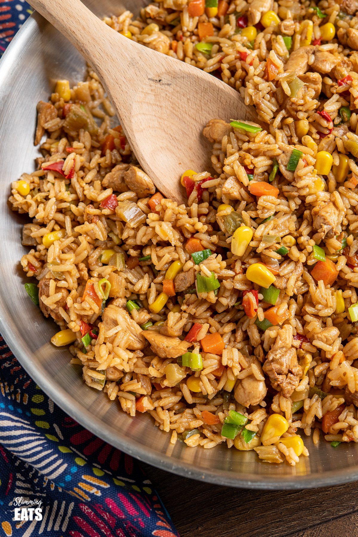 close up of savoury rice in stainless steel frying pan with wooden spoon