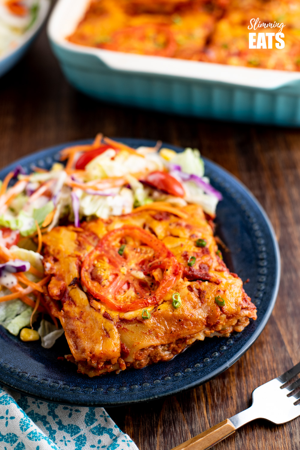 slice of spicy Mexican chicken lasagne on navy blue plate with salad