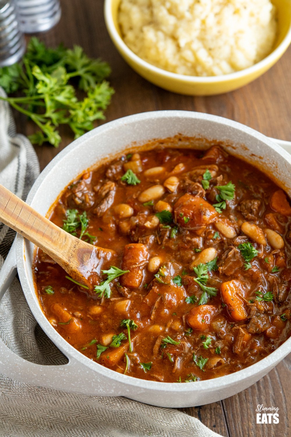 Tuscan Beef Casserole in deep pot with mash in background