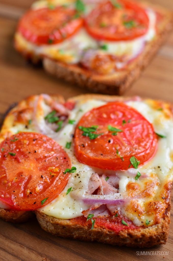 Pizza Toasts - crispy toast base smothered with pizza sauce and melted cheesy goodness. #slimmingeats #weightwatchers #pizza #bread close up on two pizza toasts on a wooden board.