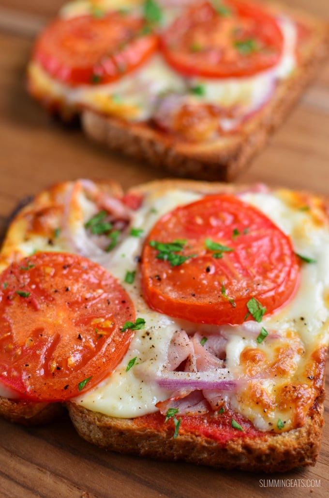 close up on two pizza toasts on a wooden board.