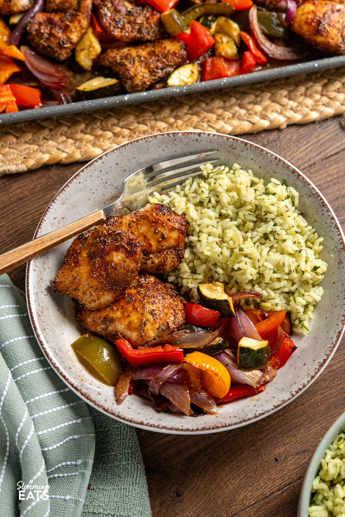 black pepper chicken, served alongside balsamic roasted vegetables and herby seasoned rice in a bowl with wooden handled fork place in left hand side of bowl 
