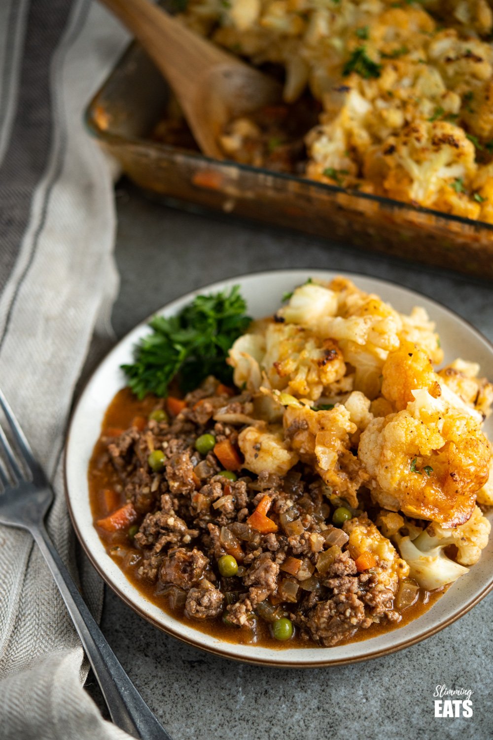 Cheesy Cauliflower Topped Pie - all the goodness of a traditional cottage pie but topped with delicious tender cheesy cauliflower florets. Gluten free, Slimming Eats and Weight Watchers friendly cheesy cauliflower topped pie dishes up in white bowl with fresh parsley.