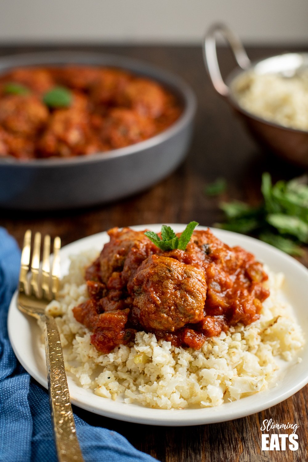 lamb and mint meatballs in a sweet and spicy sauce on a white plate with cauliflower rice and gold fork.