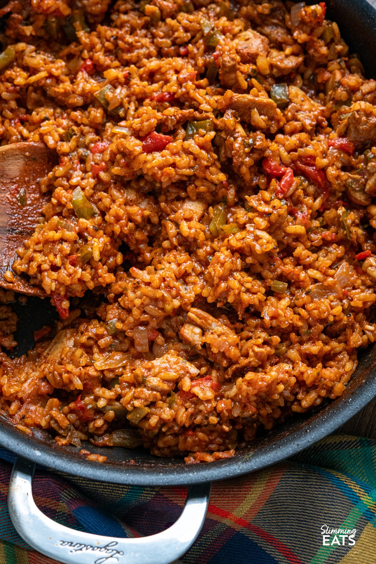 One Pot Spicy Spanish Chicken with Rice – a bold, risotto-style dish with tender chicken, smoky paprika, and creamy rice, all cooked in one pan for maximum flavour with minimal effort. close up of Spicy Spanish Chicken Rice in double handled non stick pan with wooden spoon