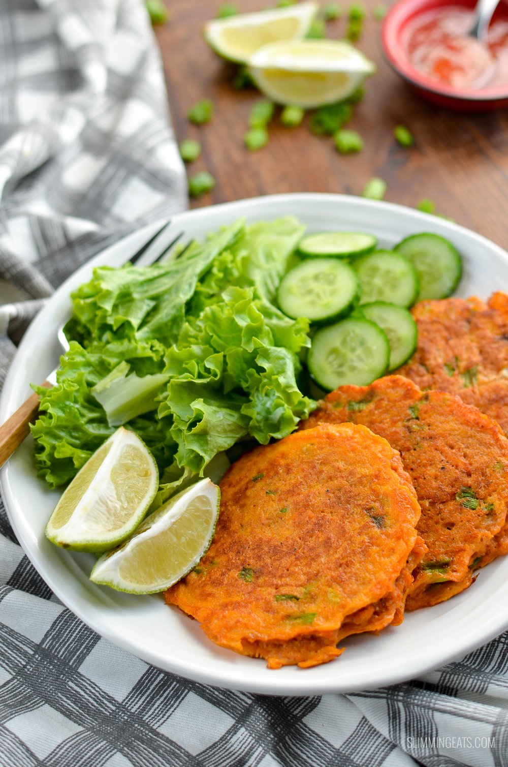 Thai Crab Cakes on a white plate with lettuce, cucumber and lime slices