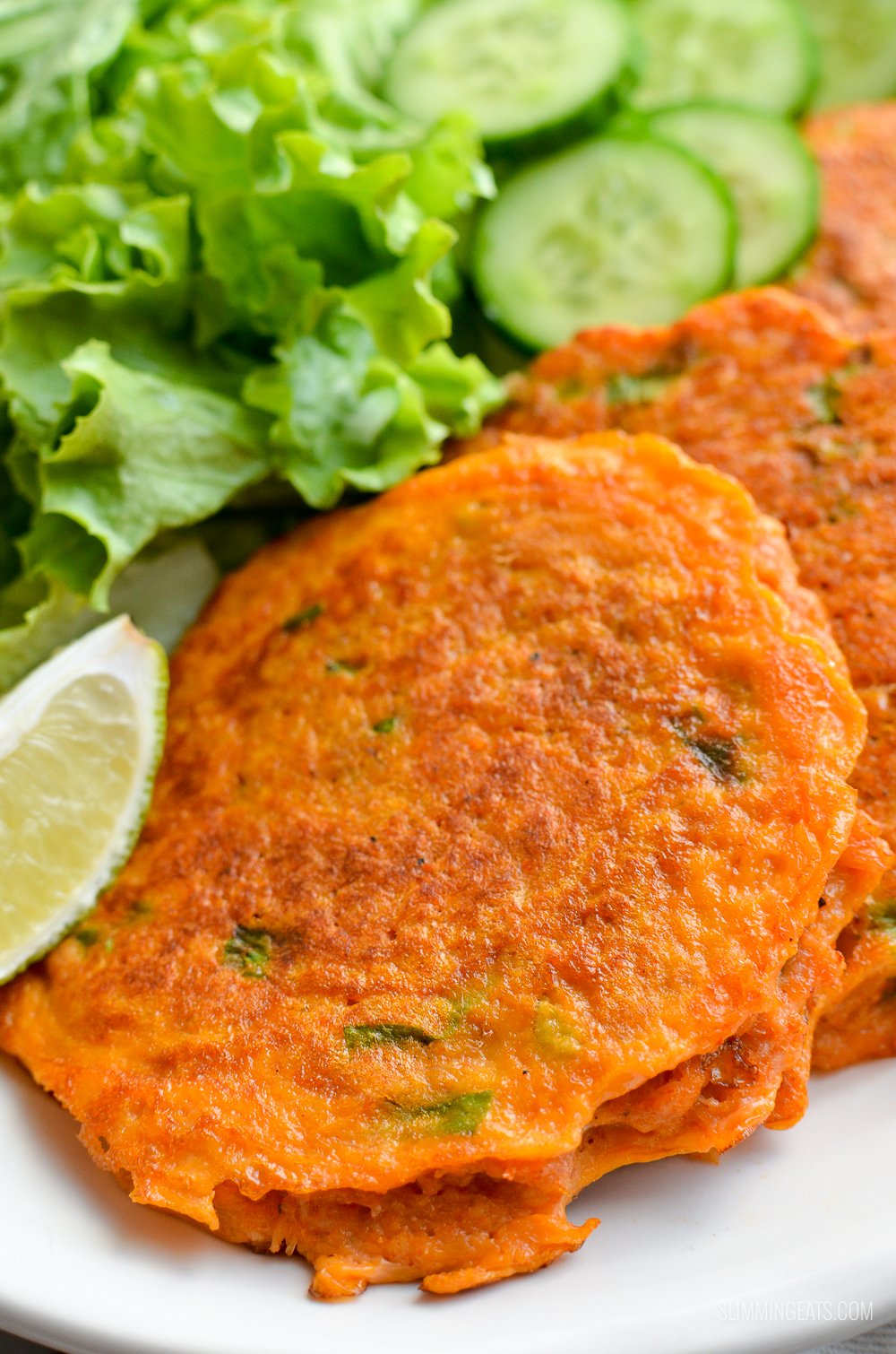 Seriously addictive Thai Crab Cakes for a perfect light meal or appetizer. #slimmingeats #weightwatchers #Thai #crab #glutenfree #dairyfree #paleo close up of Thai crab cake on a white plate with salad and cucumber