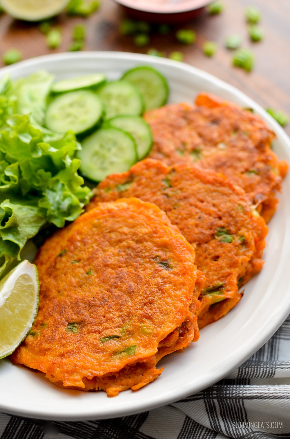 3 thai crab cakes on a white plate with salad and cucumber