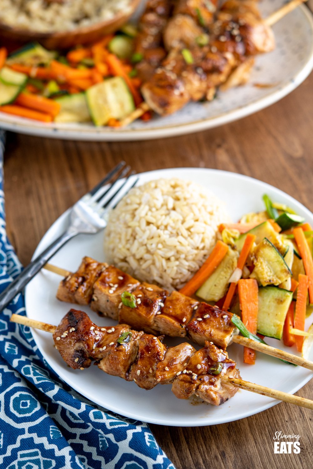 Yakitori Chicken Skewers on white plate with serving brown rice and sesame vegetables