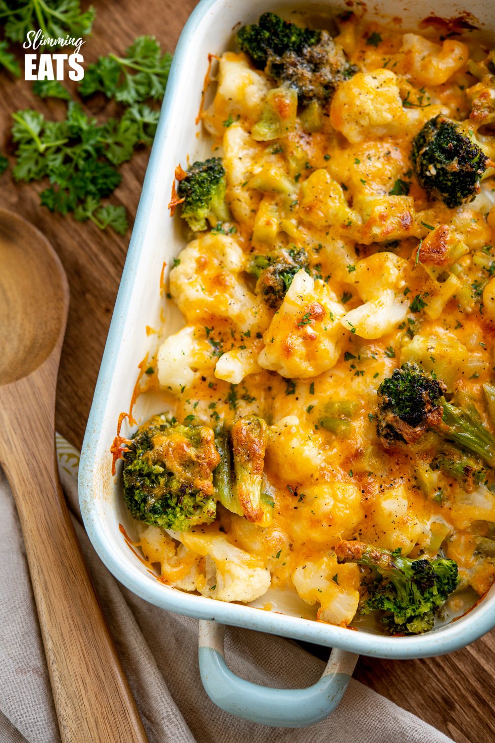 over the top view of Creamy Cheesy Vegetable Bake in enamel baking dish on wooden board