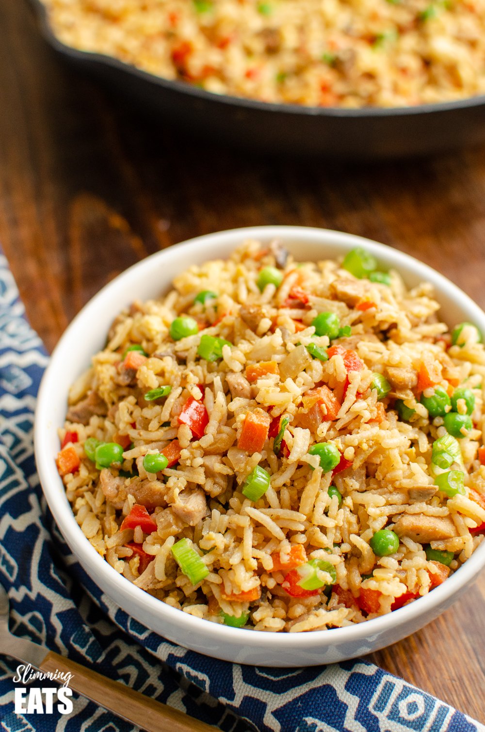 chicken fried rice in white bowl on wooden board with blue patterned placemat