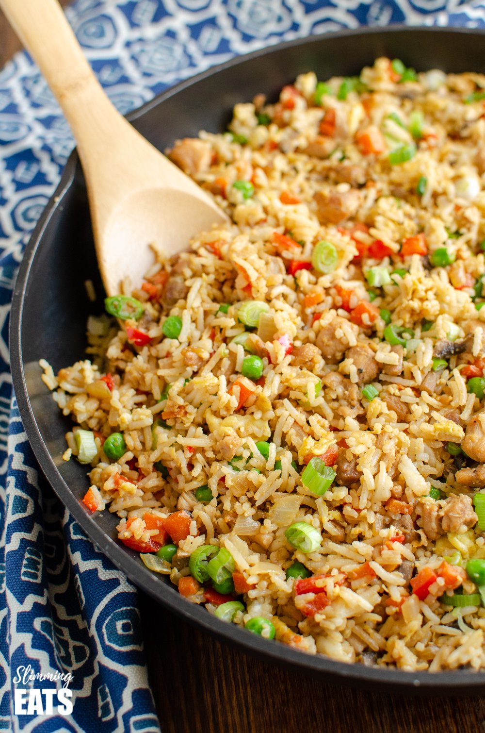 chicken fried rice in frying pan with wooden spoon