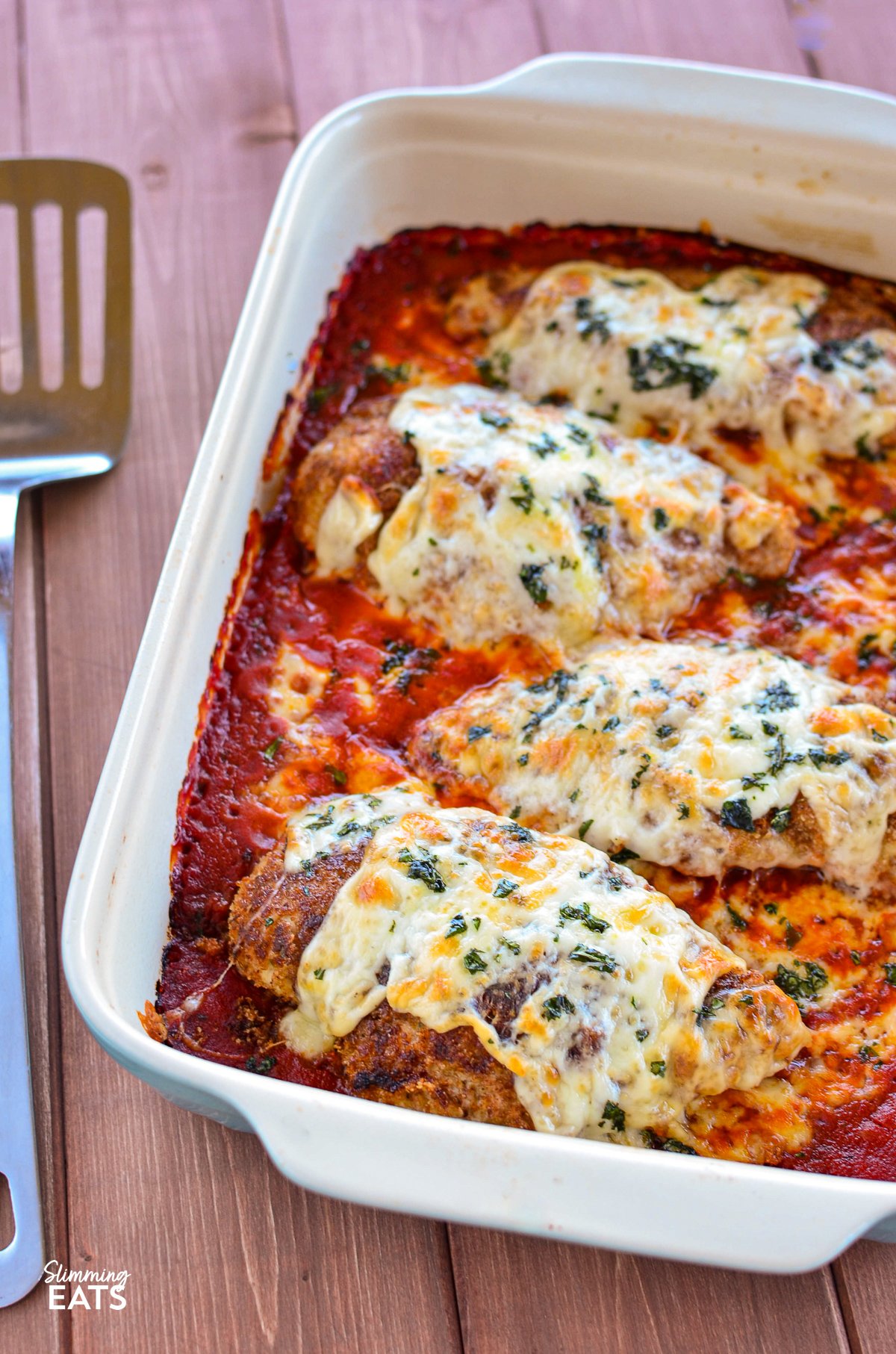 Chicken Parmesan in le creuset oven baking dish with spatula to left hand side