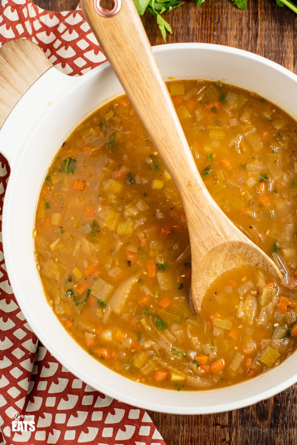 hearty vegetable soup in pan with wooden spoon