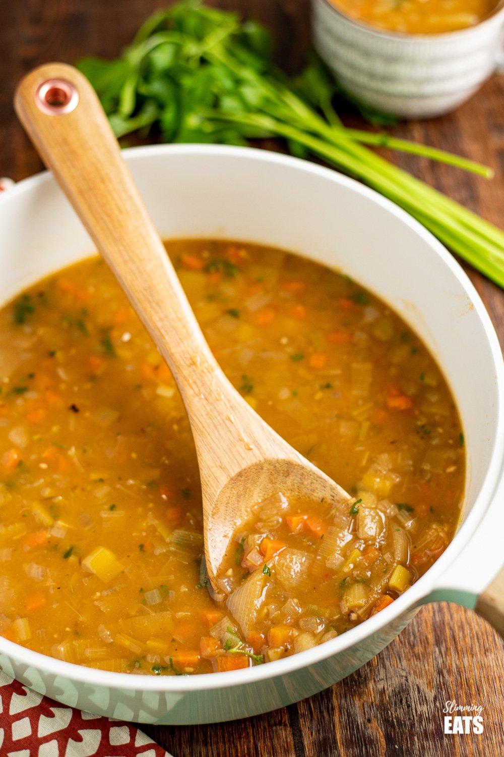 hearty vegetable soup in pan with wooden spoon