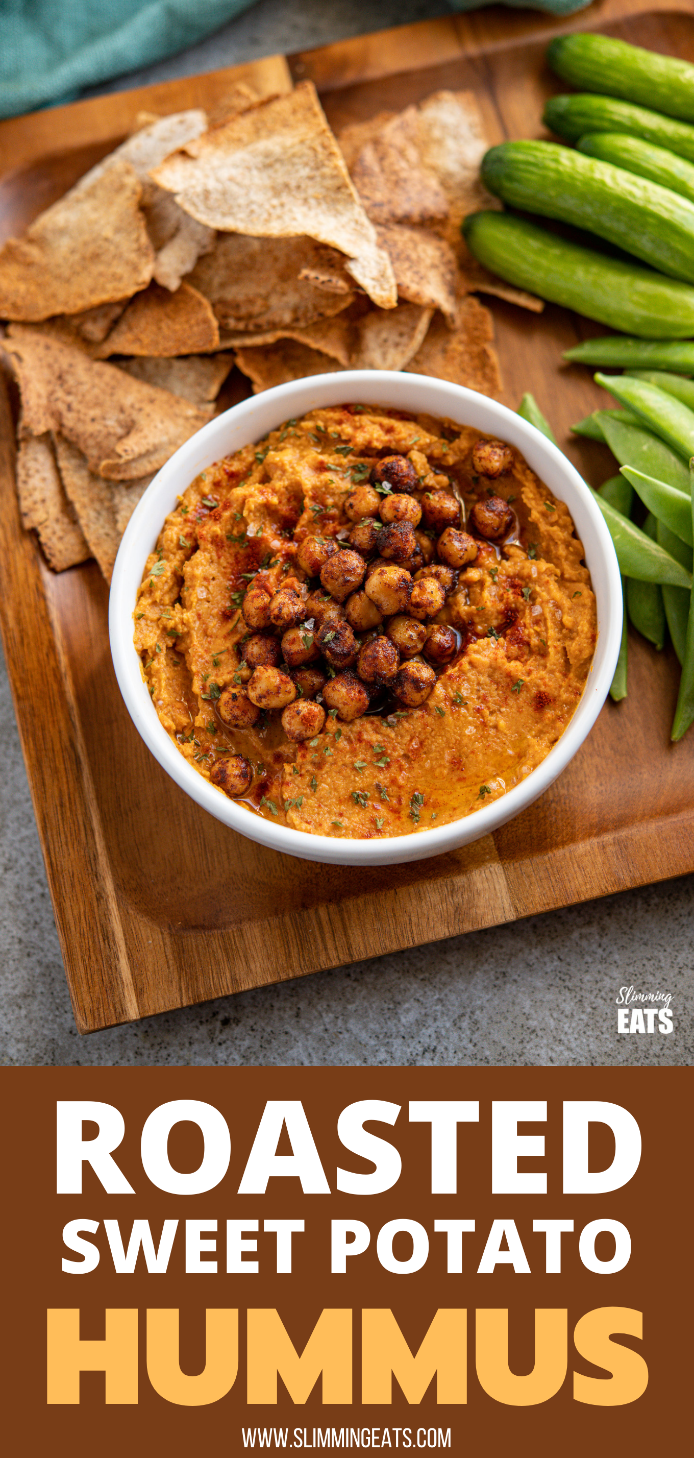 roasted sweet potato hummus topped with toasted chickpeas in a white bowl on wooden tray with pita chips and vegetable crudites