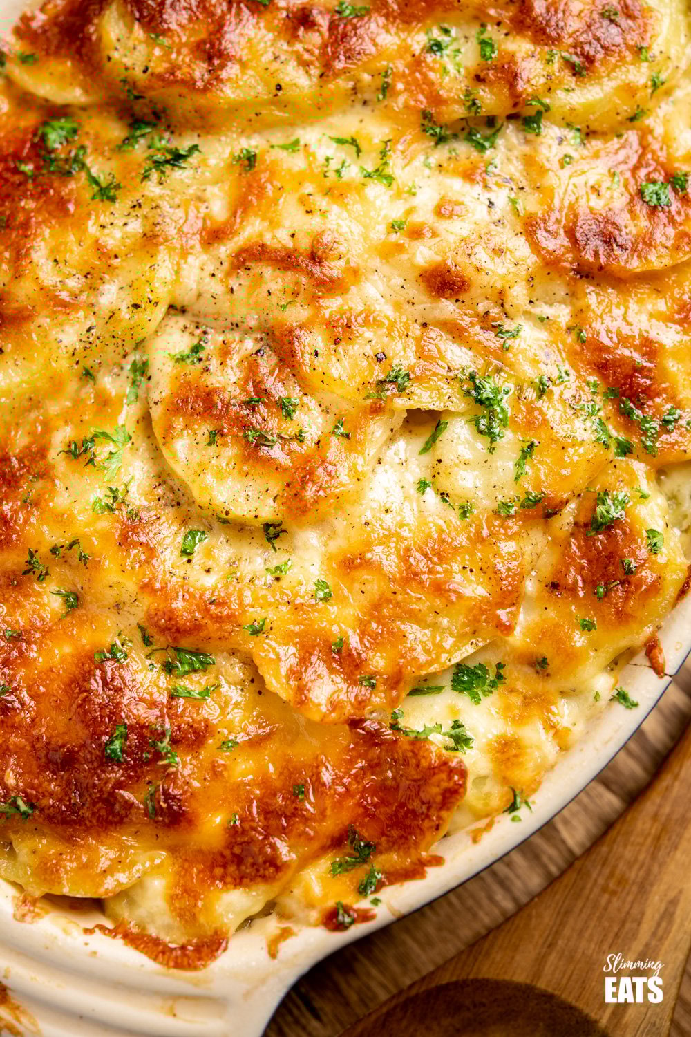 Delicious Cheesy Leek and Potato Bake - easy to make and perfect to enjoy as a side dish or even a main course. Gluten Free, Vegetarian, Slimming World and Weight Watchers friendly close up of leek and potato bake in le creuset oval baking dish