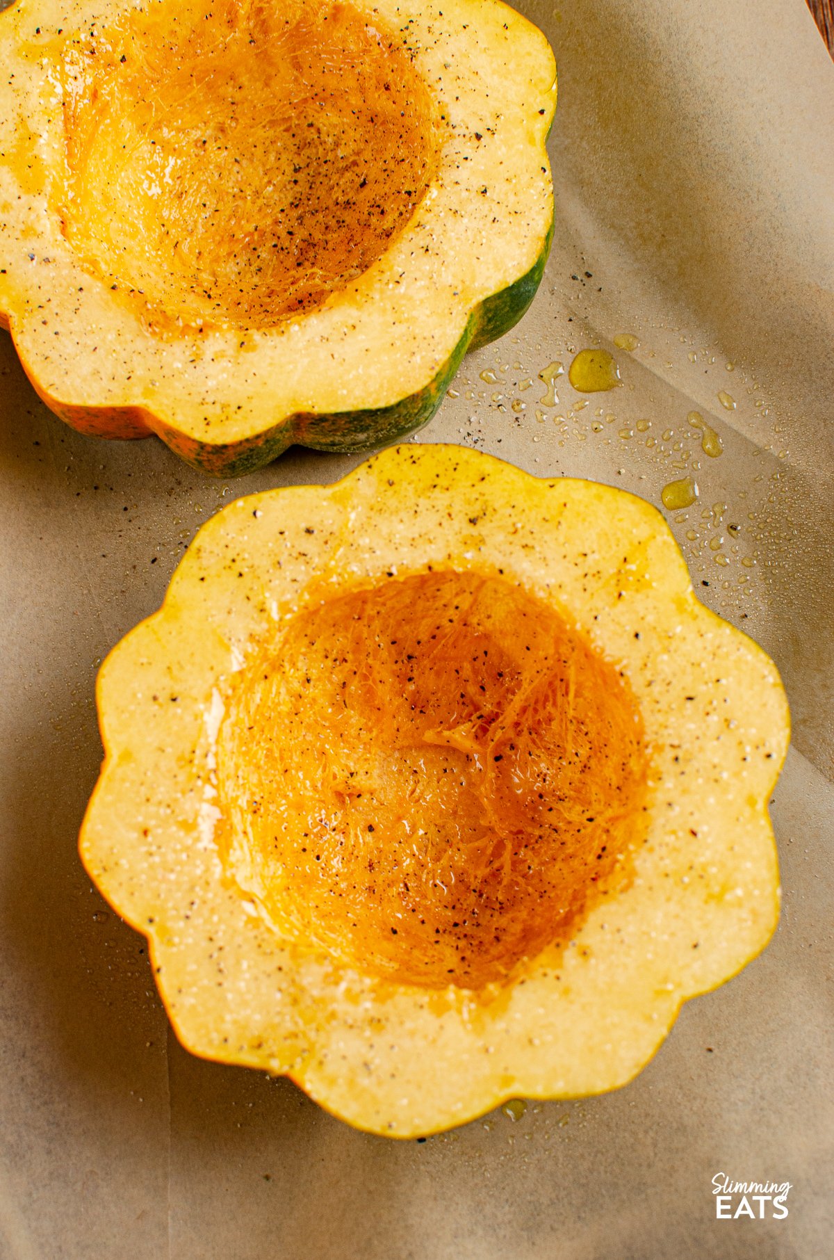 cut in half acorn squash on parchment lined tray