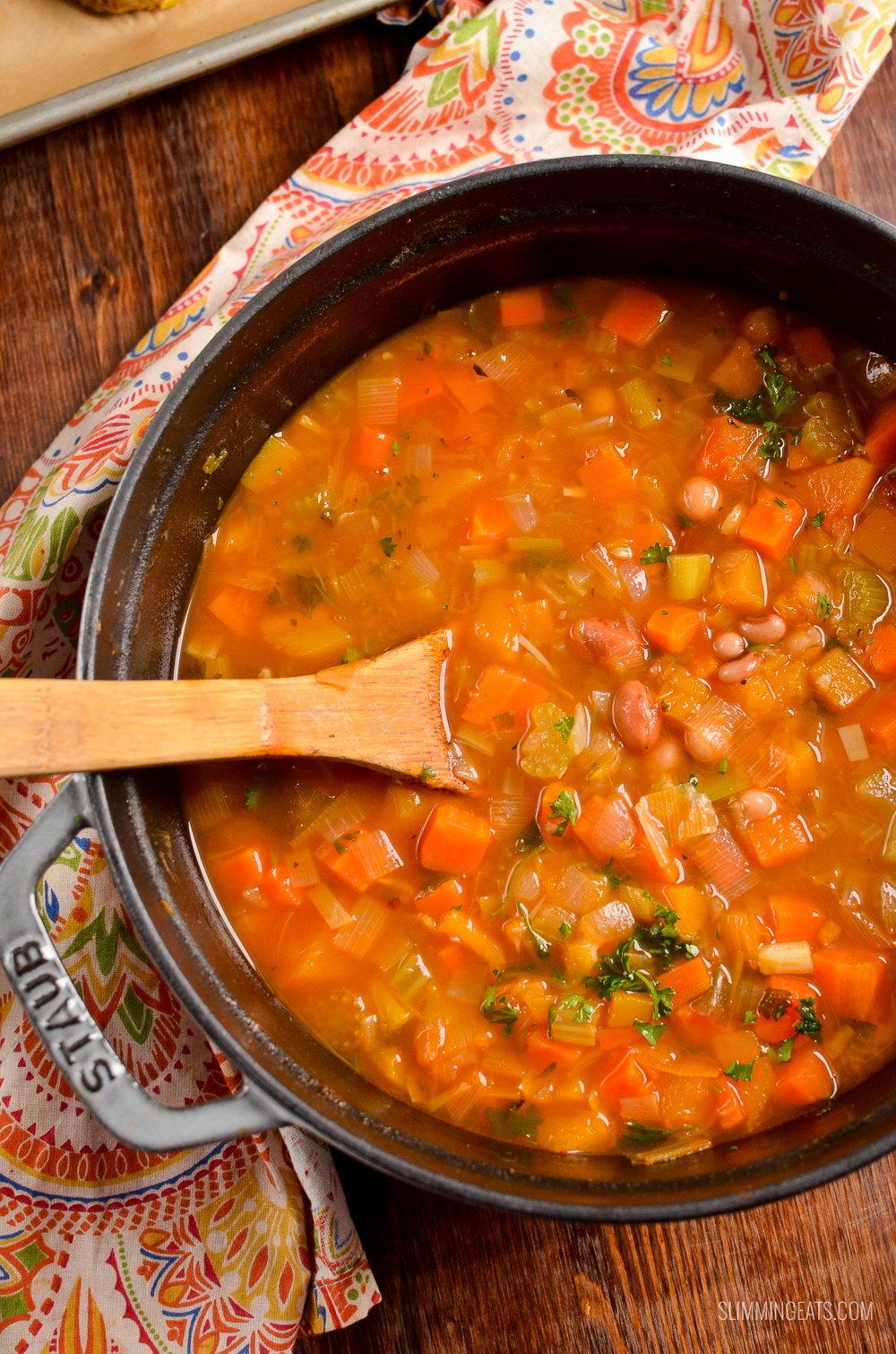 vegetable and bean stew in cast iron pot with wooden spoon