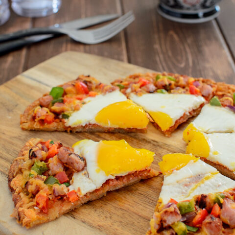 sliced breakfast hash brown pizza with coffee and knife and fork