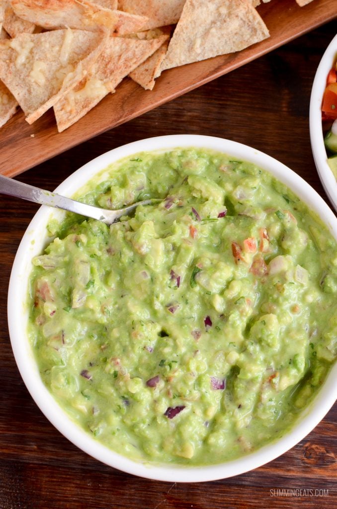 over the top view of pea guacamole in white dish with pita chips