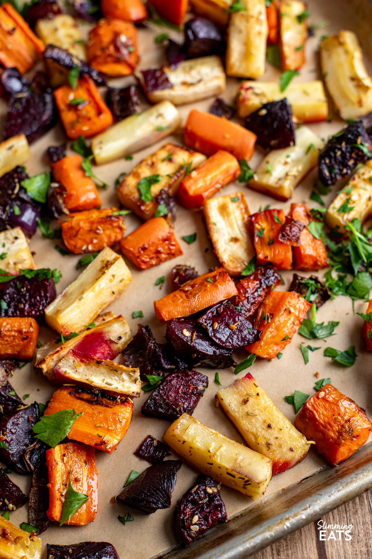 close up of roasted parsnips, carrot, beets and onion on a parchment lined tray