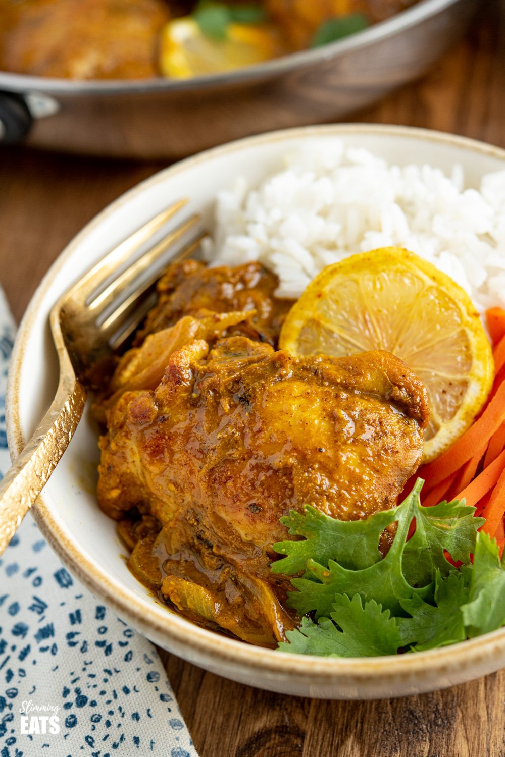 close up of white bowl of lemon chilli chicken with rice, carrots and coriander. 